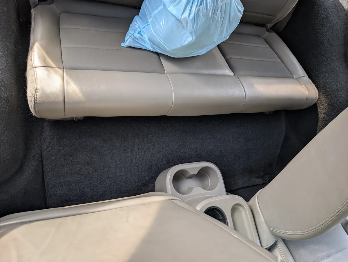 Jeep Wrangler rear cabin after detailing, showing dark carpet with substantially less visible hair and debris and cleaner cupholders.
